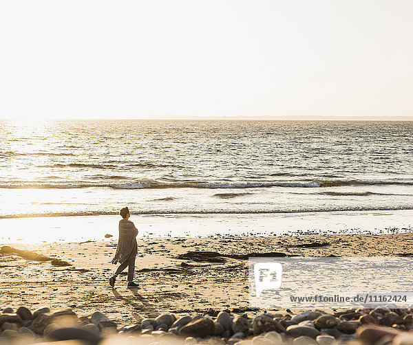 Frankreich  Halbinsel Crozon  Frau geht bei Sonnenuntergang am Strand spazieren