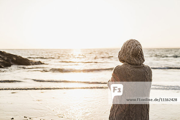 France  Crozon peninsula  woman wearing a cardigan on the beach at sunset