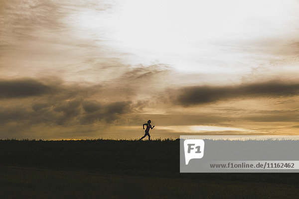 Silhouette of woman running at dusk