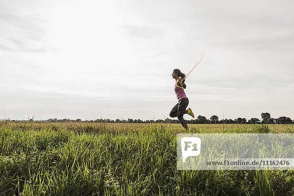 Young woman skipping rope in rural landscape