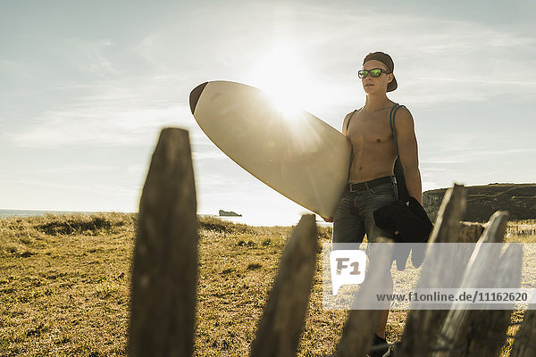 Junger Mann mit Surfbrett an der Küste
