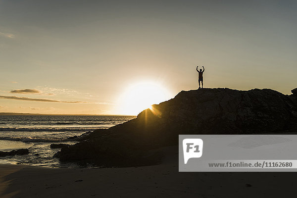 France  crozon peninsula  young man on rock at sunset