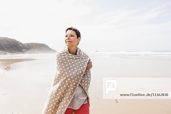 Reife Frau in eine Decke am Strand gewickelt
