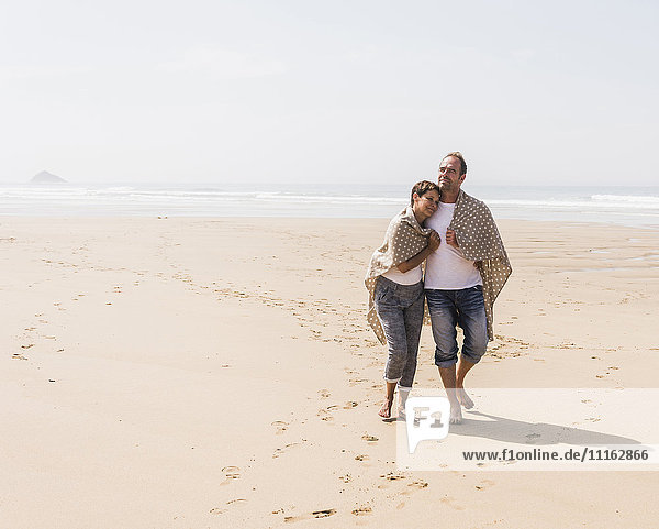 Ein reifes Paar  das am Strand spazieren geht.