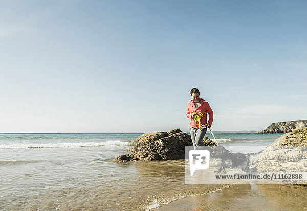 Reife Frau beim Spaziergang mit Hund am Meer