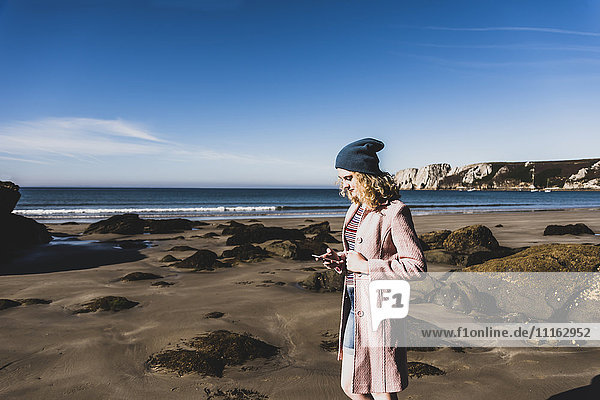 Frankreich  Halbinsel Crozon  Teenagermädchen mit Handy am Strand