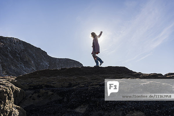 Frankreich  Halbinsel Crozon  Teenager-Mädchen  das an der Küste auf Felsen läuft