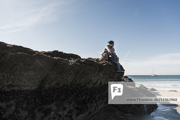 Frankreich  Halbinsel Crozon  Teenagermädchen auf Felsen am Strand sitzend