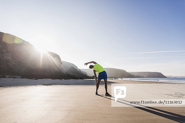 Frankreich  Halbinsel Crozon  sportlicher junger Mann  der sich am Strand ausstreckt