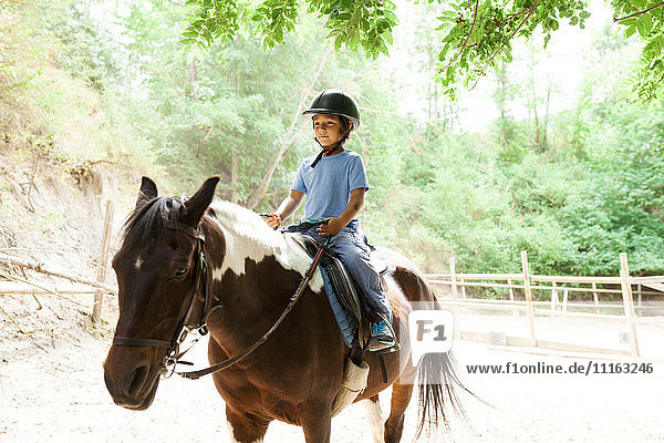 Little boy riding horse at riding school