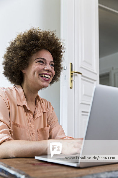 Lachende junge Frau mit Laptop