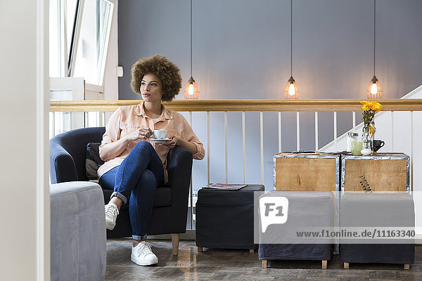 Junge Frau sitzend im Sessel in einem Café