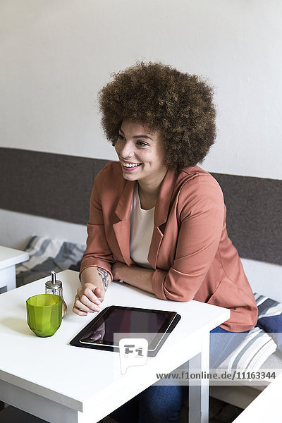 Lächelnde junge Frau mit digitalem Tablett im Cafe
