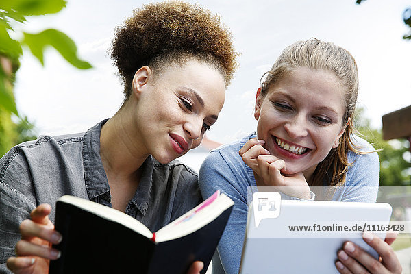Zwei lächelnde junge Frauen mit Tagebuch und Tablettenausläufern