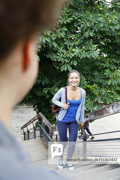 Lächelnde junge Frau beim Treppensteigen im Park