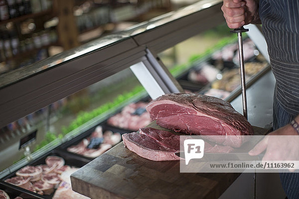 Butcher cutting raw steak on wooden board
