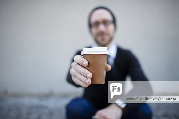 Junger Mann mit Kaffee zum Mitnehmen