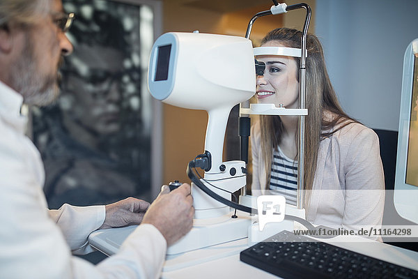 Junge Frau macht Sehtest beim Augenarzt