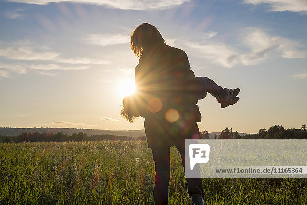 Frau mit Sohn auf einem Feld bei Sonnenuntergang