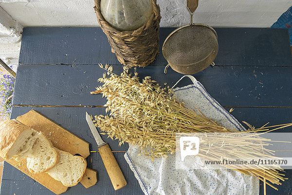 Weizen  geschnittenes Brot  Sieb und Flasche auf der Bank