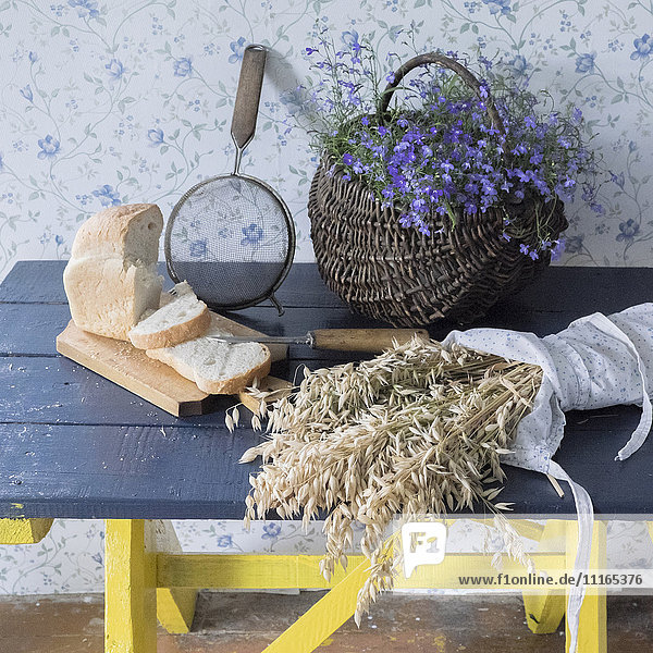 Weizen  geschnittenes Brot  Sieb und Blumen auf der Bank