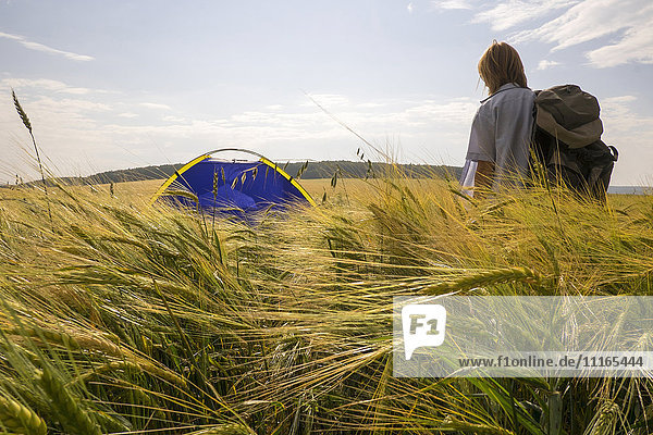 Caucasian woman standing in field near camping tent