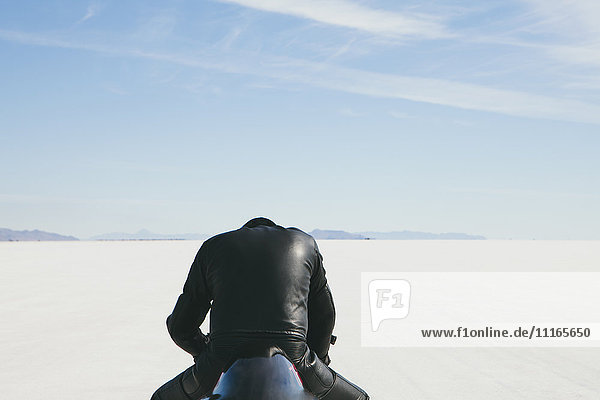 Mann in schwarzem Leder  sitzt auf einem Motorrad und bereitet sich auf ein Rennen auf den Bonneville Salt Flats vor  Kopf nach unten.