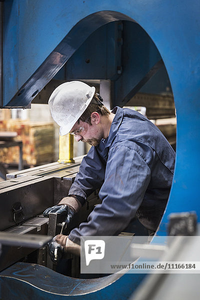 Caucasian worker fabricating metal in factory
