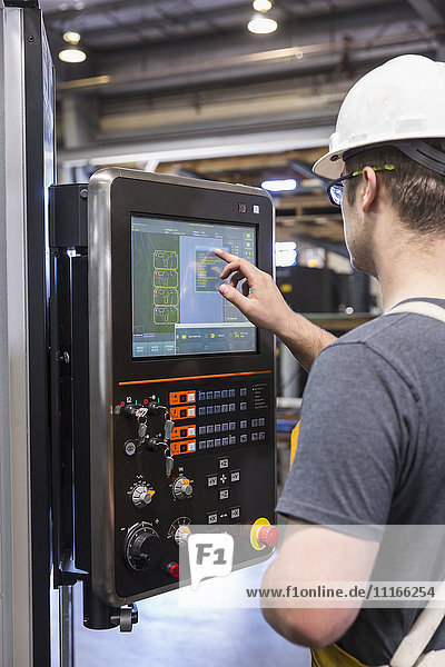 Caucasian worker using control panel in factory
