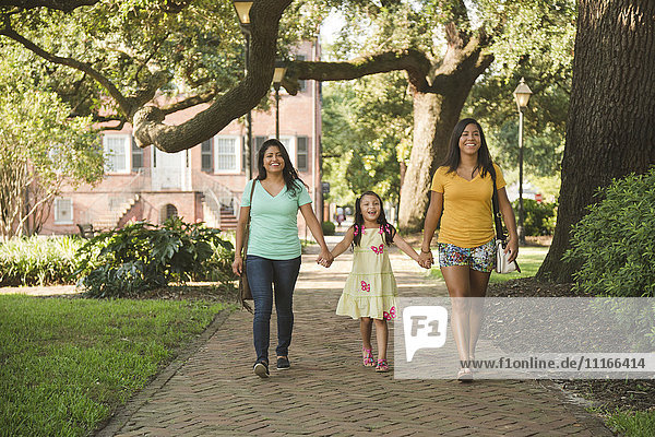 Hispanische Mutter und Töchter gehen im Park spazieren