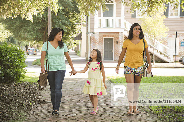 Hispanische Mutter und Töchter gehen im Park spazieren