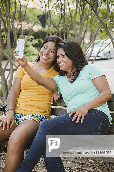Hispanische Mutter und Tochter posieren für ein Selfie mit dem Handy