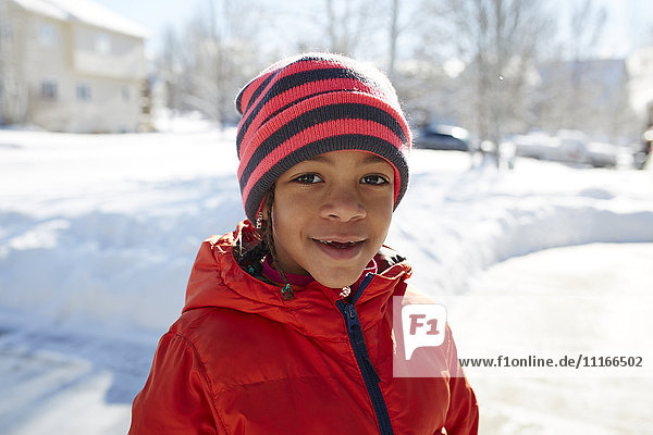 Smiling Mixed Race girl wearing hat and coat in winter