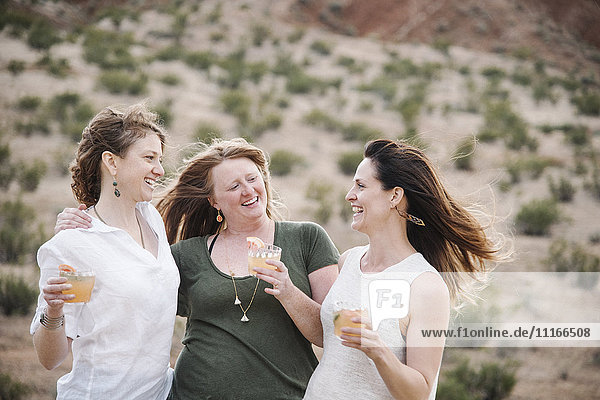 Drei Frauen stehen in einer Wüstenlandschaft.