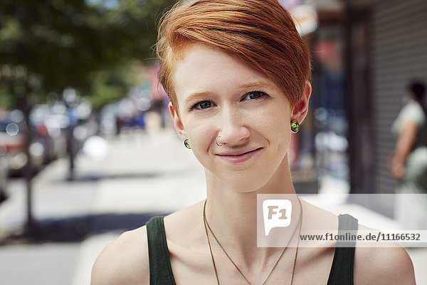 Caucasian woman with nose ring smiling on city sidewalk