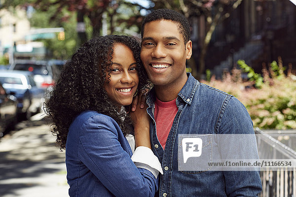 Smiling couple posing on city sidewalk