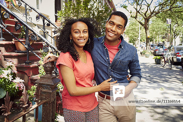 Lächelndes Paar posiert auf dem Bürgersteig der Stadt