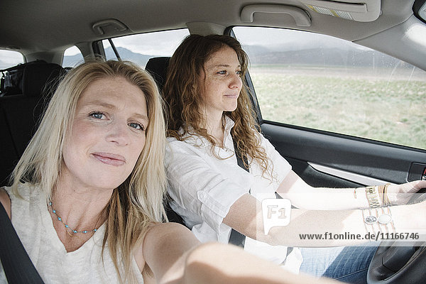 Two women in a car on a road trip  a selfie of the driver and passenger.