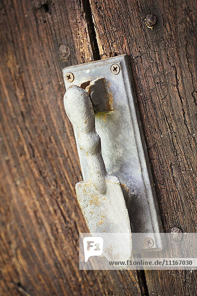 Ein Türklopfer an einer alten abgenutzten Tür in Form einer Handkelle.