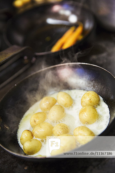 Kleine Kartoffeln  die in einer Bratpfanne auf dem Herd in einer Kneipenküche sautiert werden.