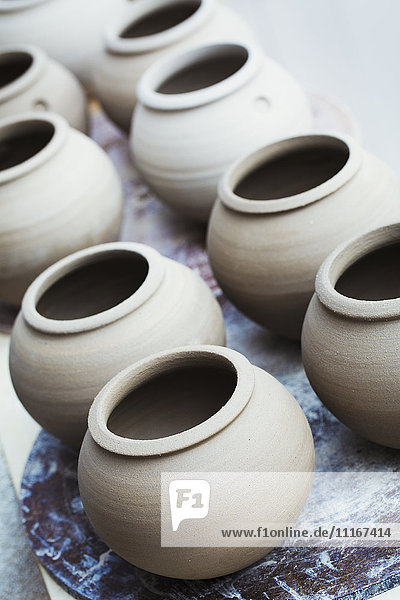A row of handthrown pots  vases with round tops.