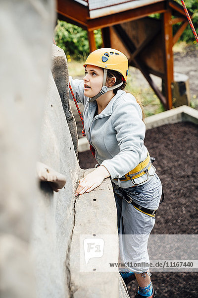 Kaukasische Frau beim Klettern an der Kletterwand
