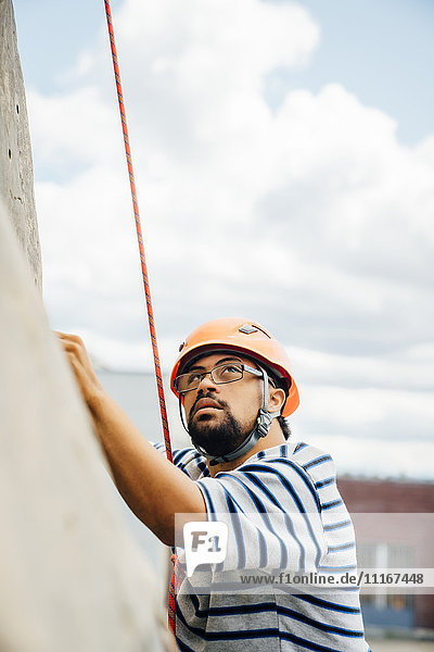 Mixed Race man climbing rock climbing wall