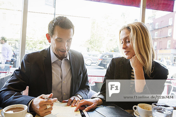 Businesswoman and businessman sitting at a table in a cafe  a working lunch  a meeting.
