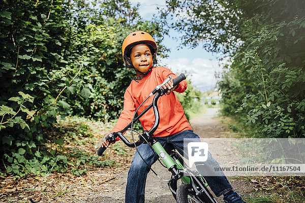 Black boy riding bicycle with helmet