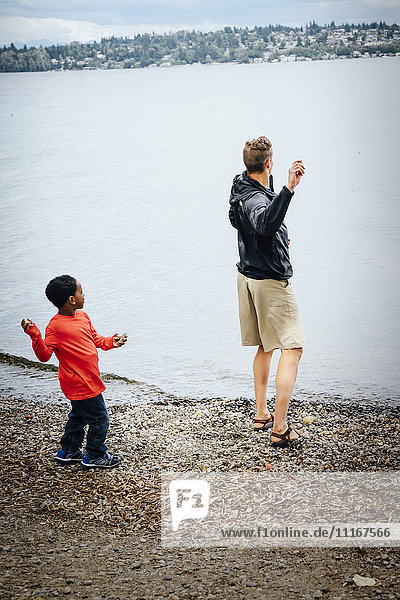 Father and son throwing rocks into river