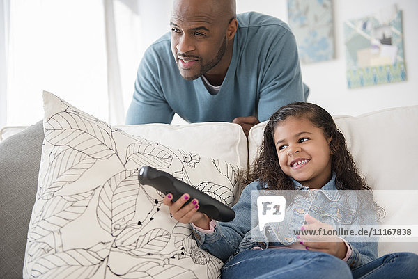 Father and daughter watching television on sofa