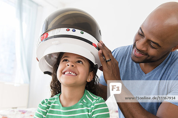 Vater setzt seiner Tochter den Astronautenhelm auf