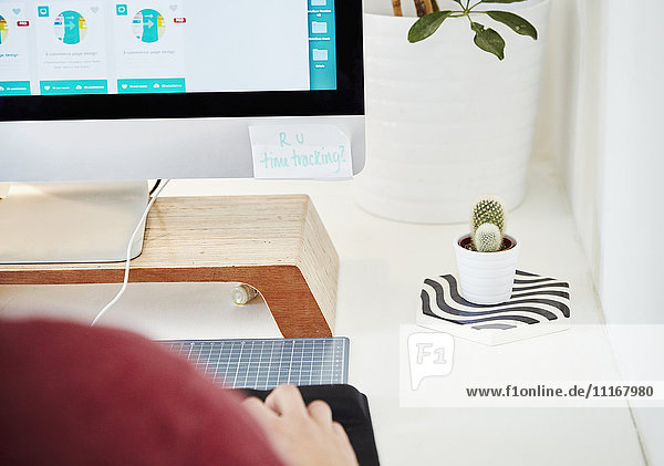 Ein Arbeitsplatz in einem Büro  Computerbildschirm  Tastatur und Kaktuspflanze. Blick über die Schulter. Auf dem Zettel steht R U Zeiterfassung?