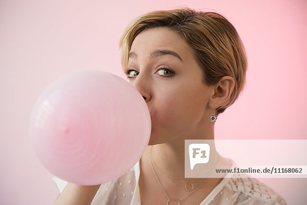 Caucasian woman inflating pink balloon